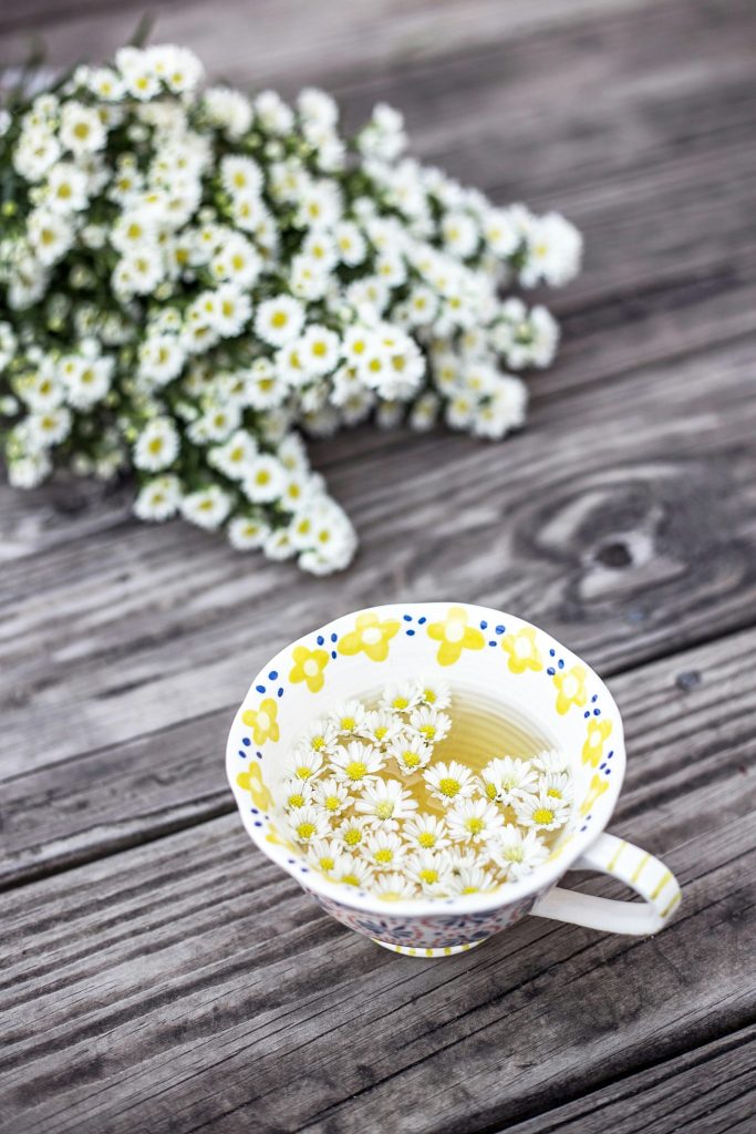 Kopp med te och kamomillblommor